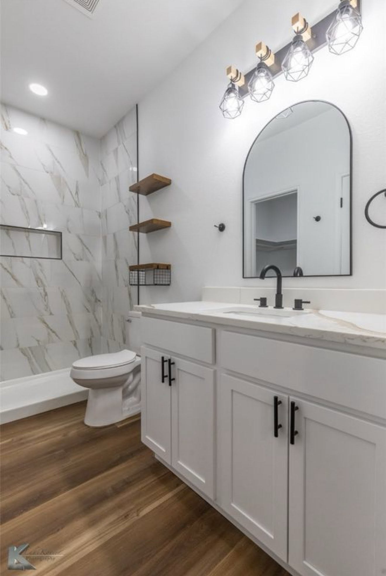 Finished bathroom with tile, vanity, lighting, and dark fixtures
