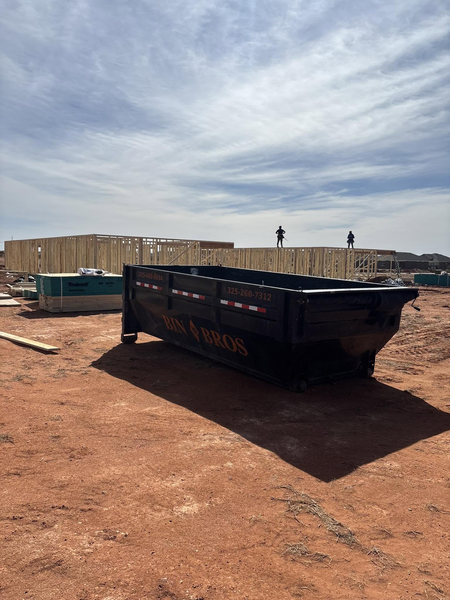 Bin Bros dumpster positioned alongside residential framing
