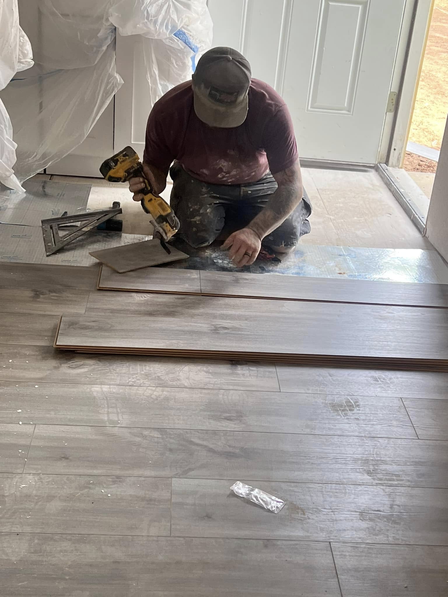 Crew member measuring and cutting a flooring board