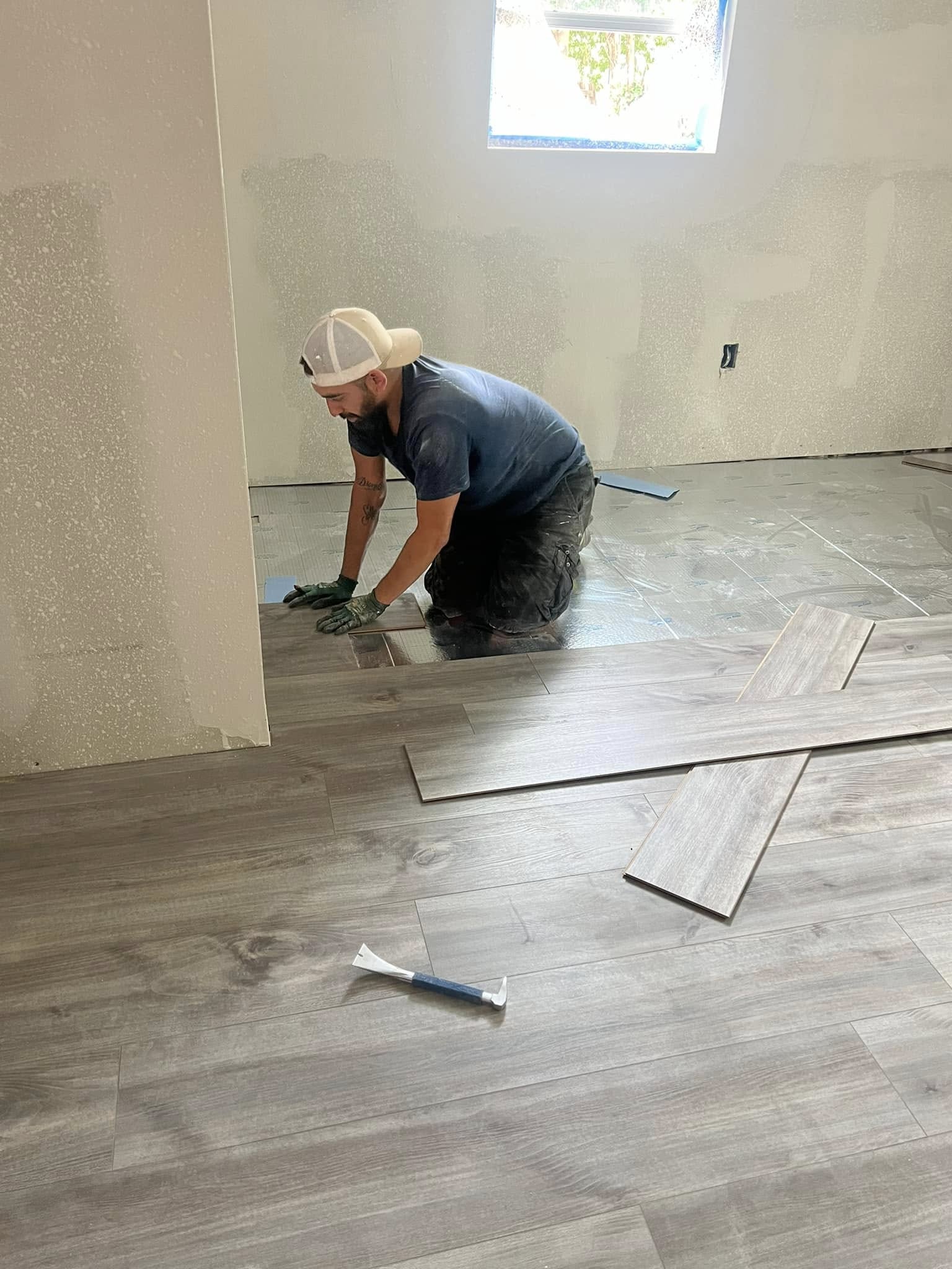 Crew member fitting flooring across an unfinished room